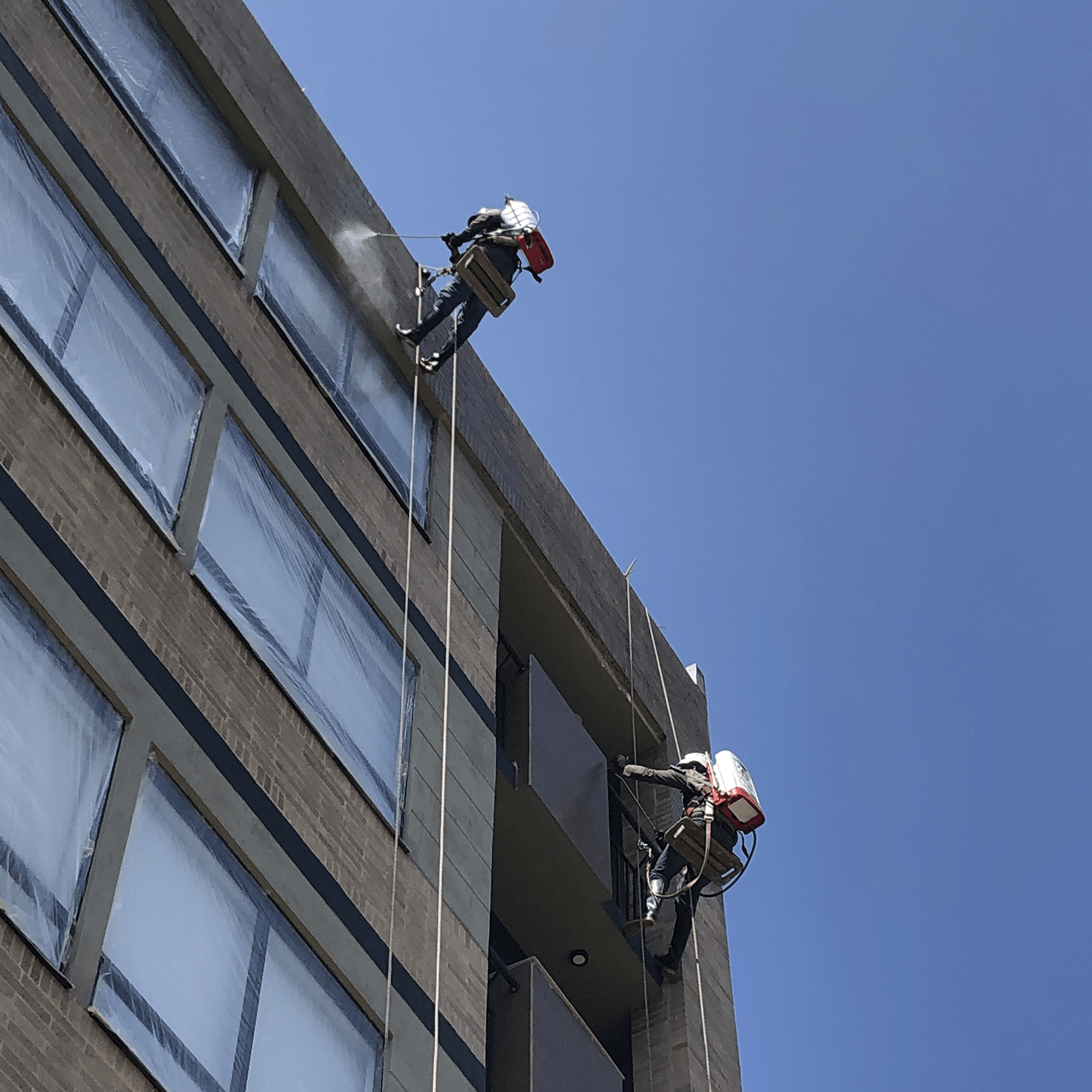Dos trabajadores de alturas realizando el hidrofugado del ladrillo con Sika transparente 10 años